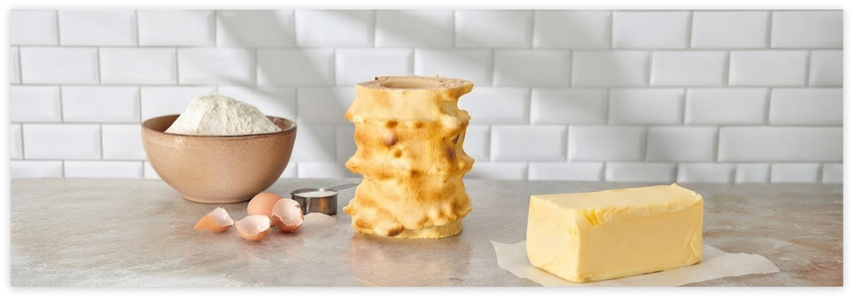 Baumkuchen ohne Überzug mit sichtbaren Schichten neben einem Butterstück